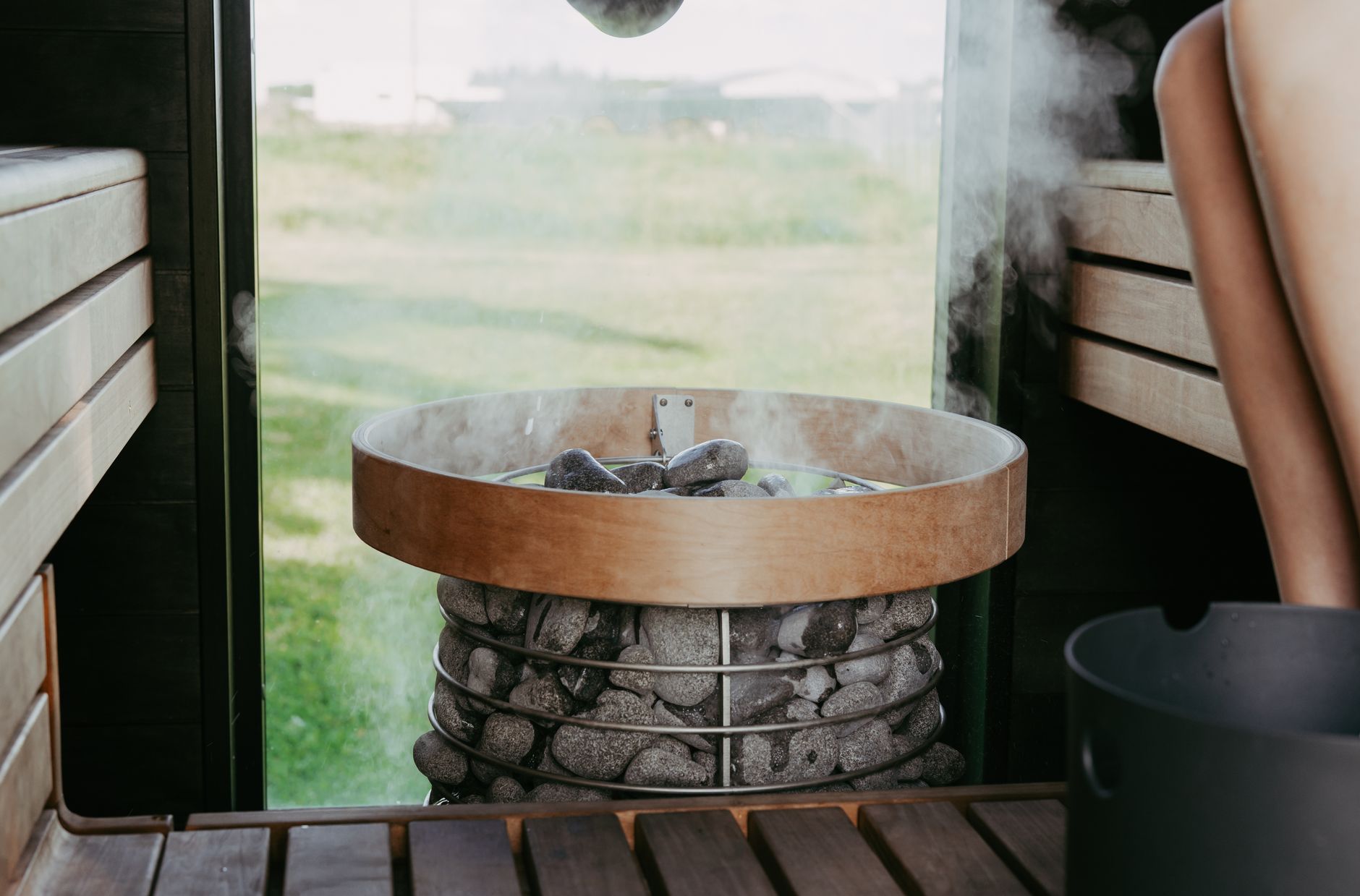 Person relaxing inside a wooden sauna with steam rising around them