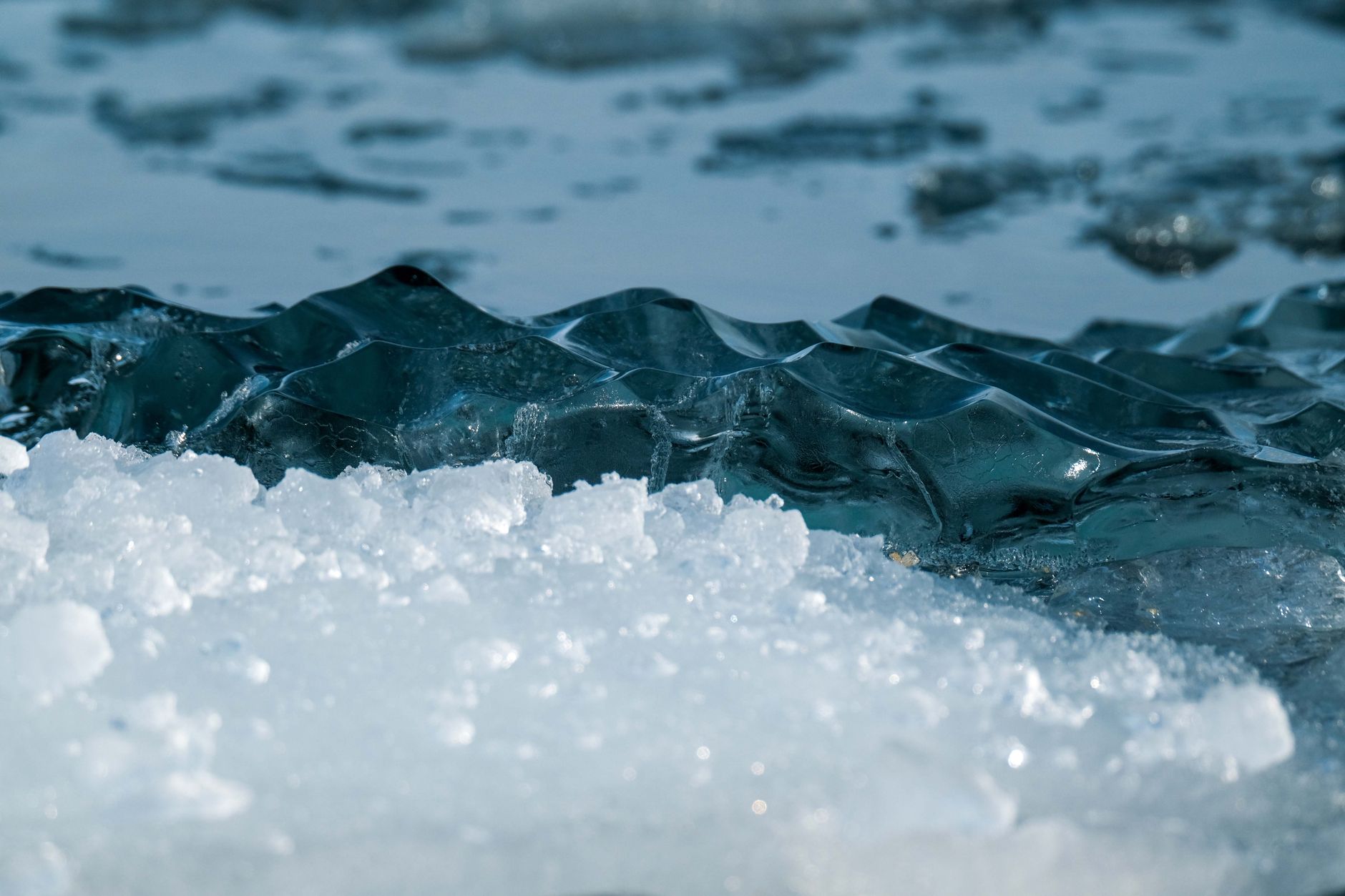 A close-up shot of dark, clear ice and white, slushy ice floating in water.