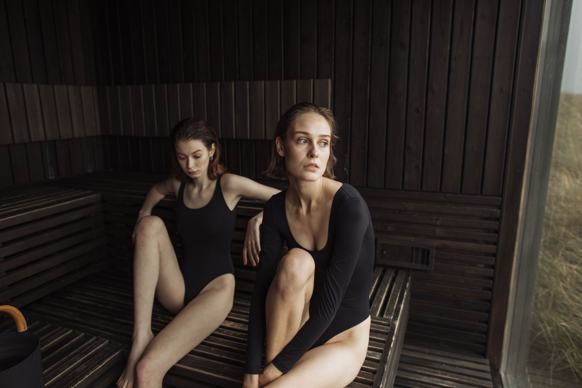 Woman sitting with eyes closed inside a wooden infrared sauna cabin