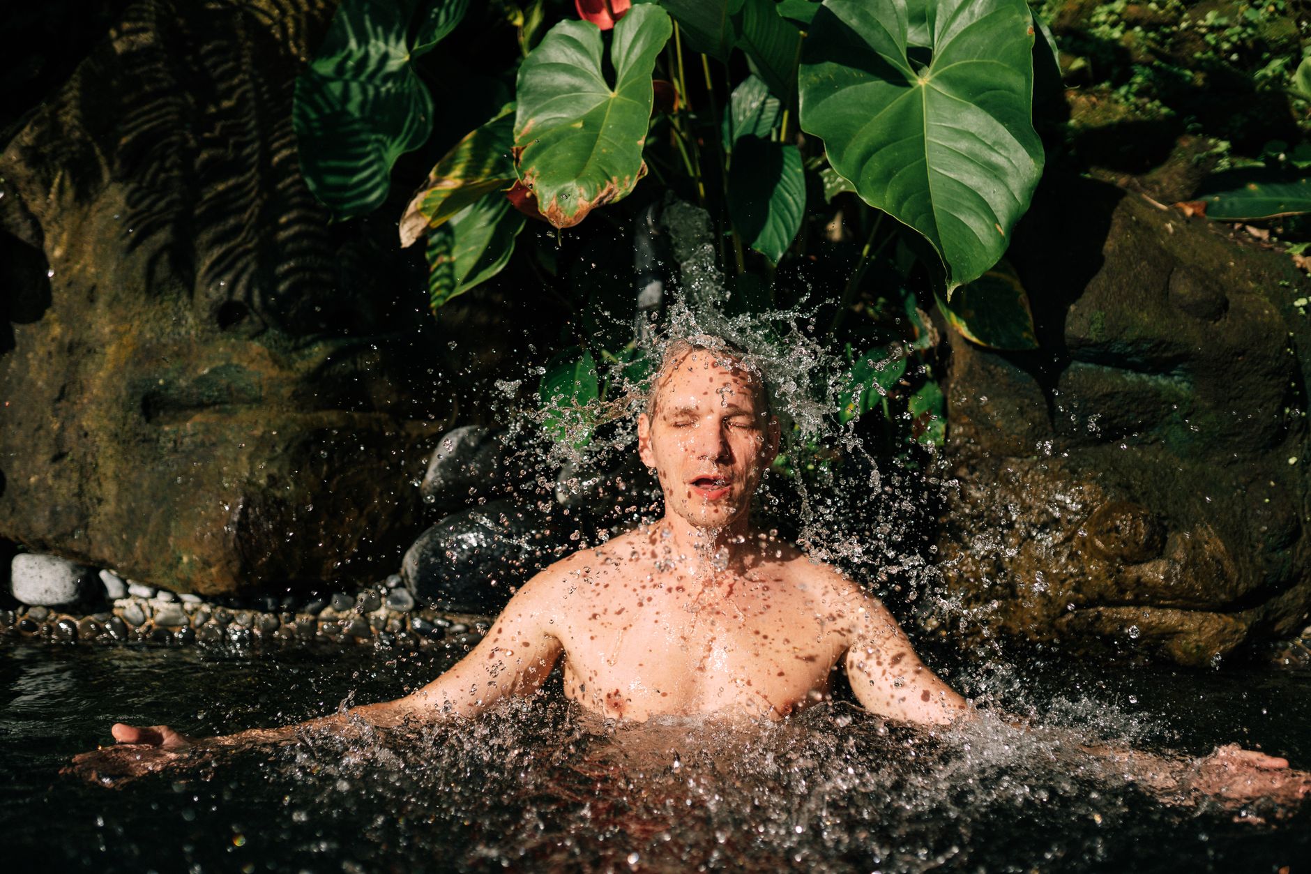 Man submerged to his chest in a black Ice Barrel cold plunge on a wooden deck